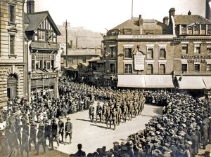 Soldiers marching through Market Square during World War I. The photograph shows the north and east of the Square with Castle Street and the Castle beyond. Dover Museum